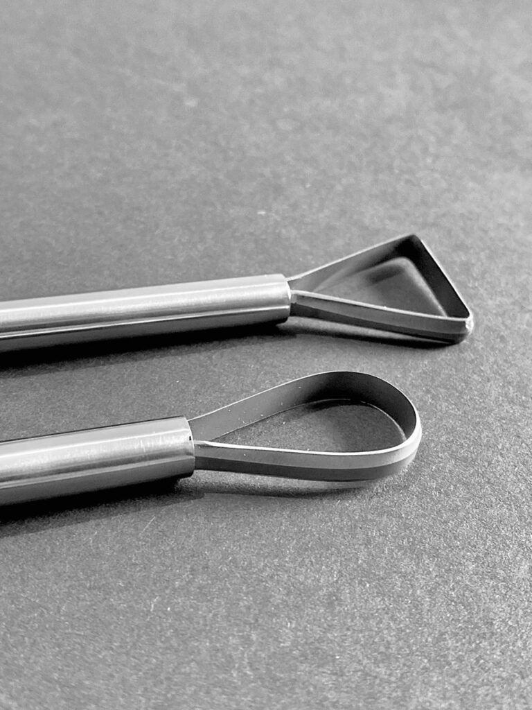 A DOUBLE ENDED TRIMMING TOOL, ONE WITH A TRIANGLE & A ROUND END.